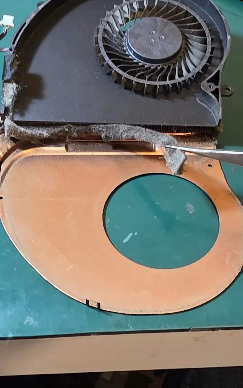 Camada de poeira sendo retirada com pinça da entrada das aletas do dissipador do Alienware 17 R5
