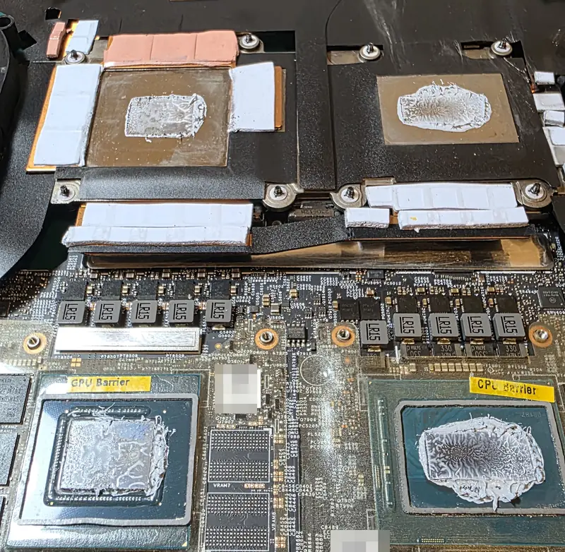 Placa-mãe do Alienware m16 R1 aberta, com pasta térmica ressecada sobre a GPU e o processador e as barreiras de metal líquido ao redor
