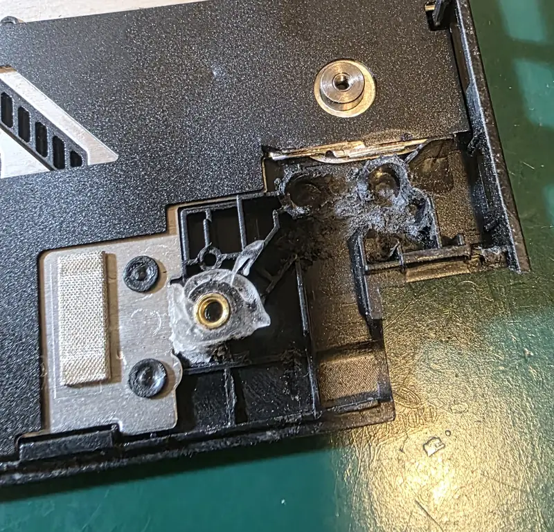 Palm rest do Asus FX517Z com a fixação da dobradiça quebrada e restos de resina ao redor da bucha