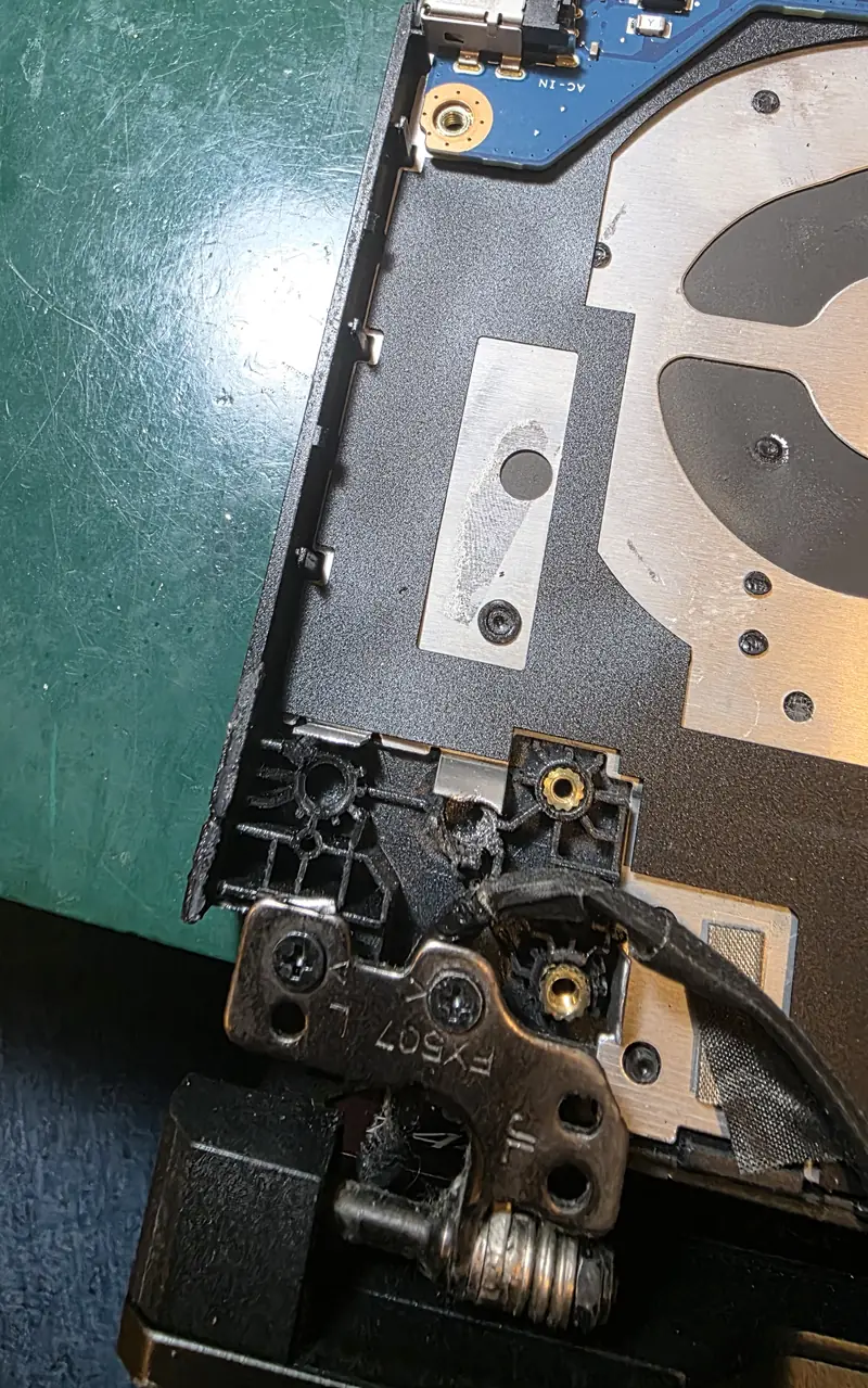 Região da dobradiça do Asus TUF Gaming A15 com a estrutura plástica das buchas do palm rest quebrada