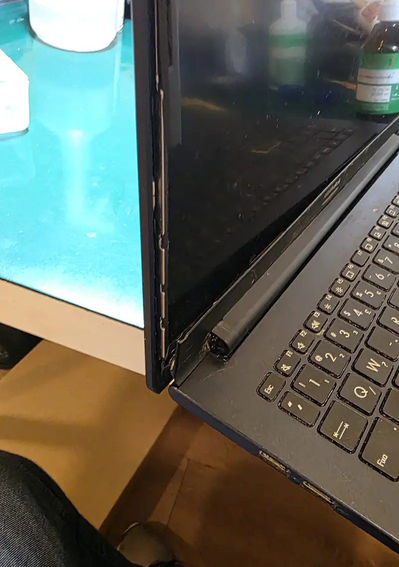 Lateral do Asus Vivobook X513EA com fresta entre a moldura e a tampa da tela perto da dobradiça