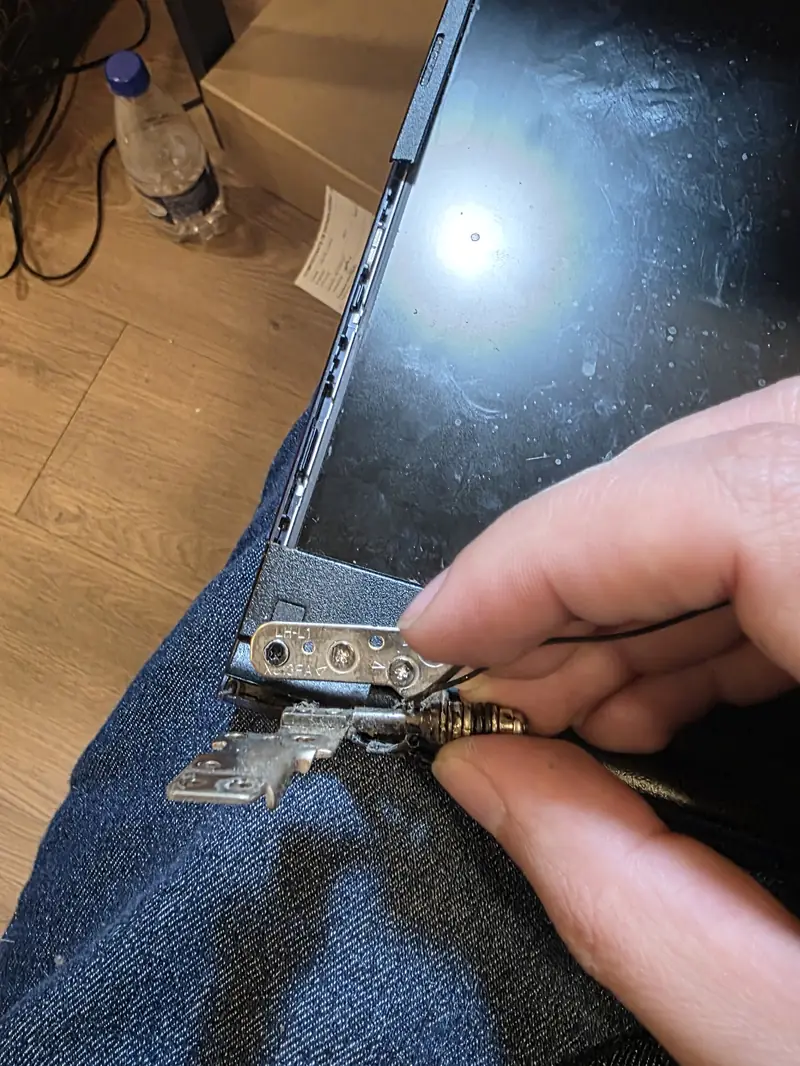 Técnico soltando os parafusos da dobradiça da tela do Asus Vivobook X513EA