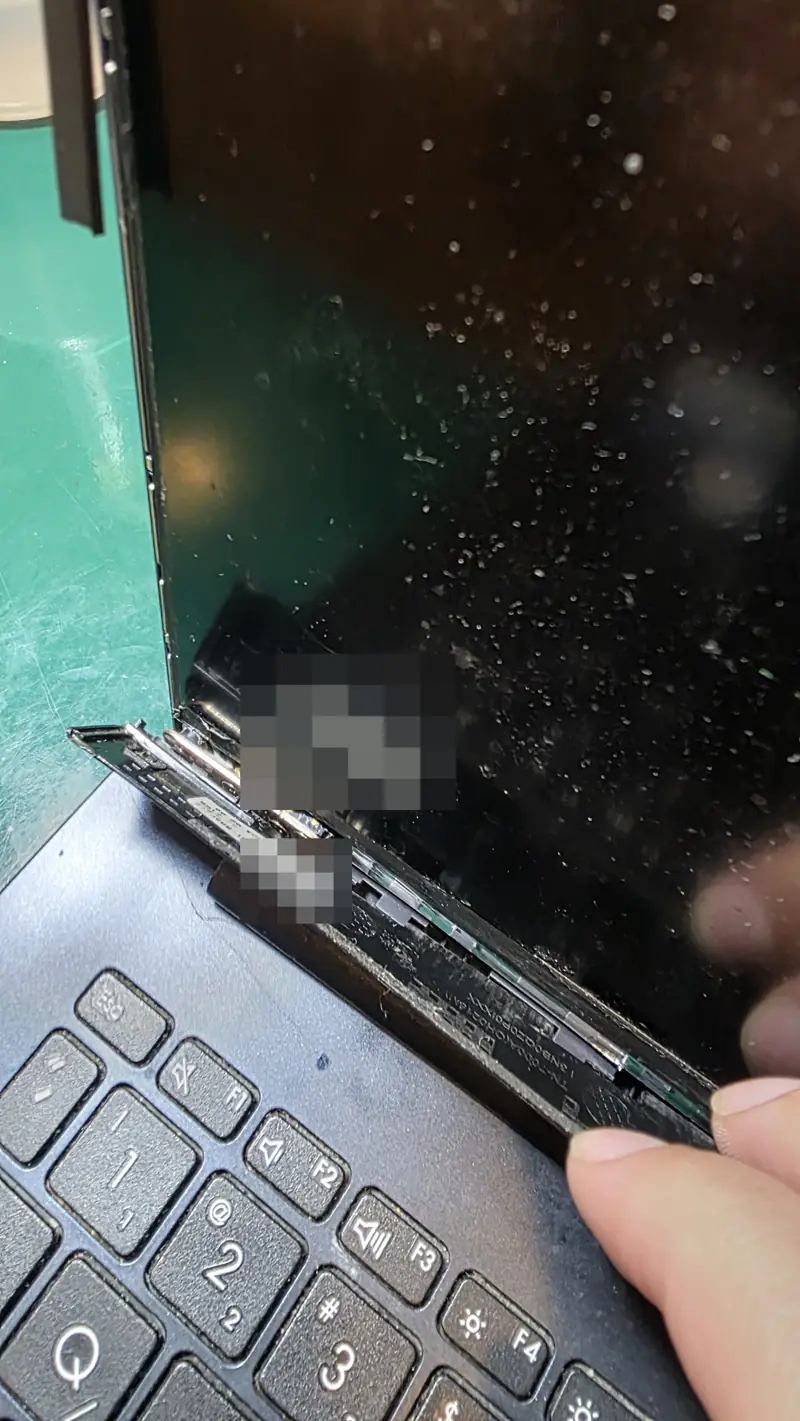 Canto da tela do Asus Vivobook X513EA com a tampa se abrindo junto à dobradiça e a moldura solta