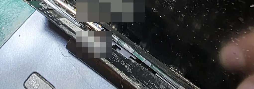 Canto da tela do Asus Vivobook X513EA com a tampa se abrindo junto à dobradiça e a moldura solta