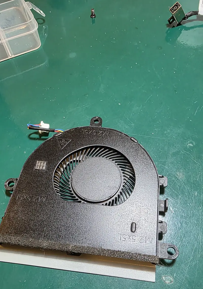 Cooler do Dell Inspiron 3501 fora do notebook para limpeza, com o conector de carga ao fundo na bancada