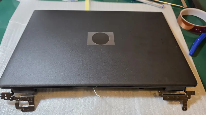 Tampa nova da tela do Dell Latitude 3520 com as dobradiças instaladas antes da montagem