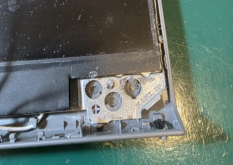 Tampa do Dell Vostro 3510 sem a moldura, mostrando a fixação da dobradiça com resina de um reparo anterior